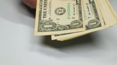 Amerikan dolarının yeniden hesaplanması. Ağır çekim. Eller beyaz arka plandaki Amerikan dolarlarını dağıtıyor. Bir dolarlık banknotlar ellerinde. Amerikan doları. Para elinde. Yüksek kalite 4K görüntü. Yakın plan.