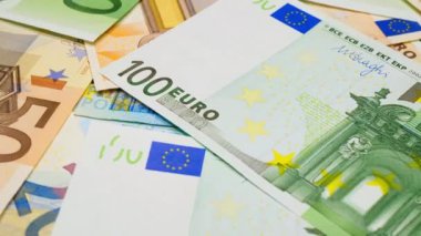 Euro dönüyor. Masada 100 Euro 'luk banknotlar dönüyor. Yeni tasarımın kâğıt Euro banknotları taşınıyor. Bir sürü 50 Euro. İş anlayışı zenginlik. Mali işler. Ekonomi. Yakın plan.