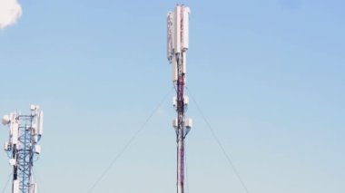 Mavi gökyüzüne karşı baz istasyonları ve beyaz bulutlar. Mobil kuledeki elektrik kabloları. Yüksek bir kulede enerji ekipmanı. Şehir baz istasyonunda yüksek teknoloji. İnternet teknolojileri. 