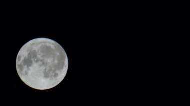 Gece gökyüzünde yükselen büyük dolunay. Ay yavaş yavaş kara gökyüzüne yükselir. Güzel bir ay ışığı gecesi yıldızsız karanlık gökyüzünde yaklaşan bir fırtına. Ay arkasına saklanıyor. Video 4k görüntüleri