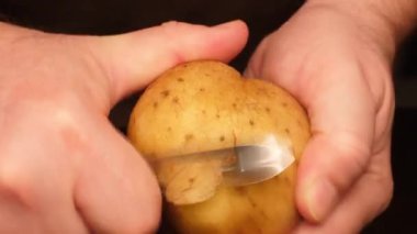 Bozuk patatesleri soyar. Siyah arka planda sebze soyacağı ile patates soyan eller. Enfekte olmuş sebzeler. Bir adam çürüme belirtileriyle patates soyar. Taze patates sebzesi ve hastalık izleri.