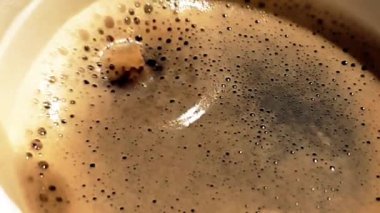 Kahve damlası, siyah arka planda köpük, yiyecek ve içecek ve rahatlama içeren bir fincan espresso italyan kahvesinin içinde süper yavaş çekimde düşüyor.