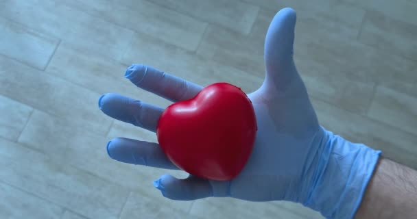 Läkare, läkare sjuksköterska håller ett hjärta och klämmer det, hjärta förebyggande och vård dagskoncept, vård och egenkärlek, med zoom-in ut — Stockvideo