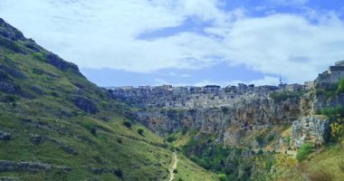 Matera 'da tatil, Gravina di Matera' da Sassi ve Santa Maria di Idris Kilisesi 'nin arka planında doğa, kültür ve doğa kavramının altında yürümek.