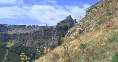 Matera 'da tatil, Gravina di Matera' da Sassi ve Santa Maria di Idris Kilisesi 'nin arka planında doğa, kültür ve doğa kavramının altında yürümek.
