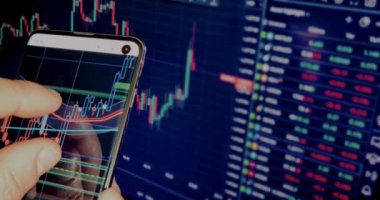 İş adamı haritayı akıllı telefonunda finans mumlarıyla kontrol eder. İş haberleri arka planda bilgisayar ekranında, finansal özgürlükle.