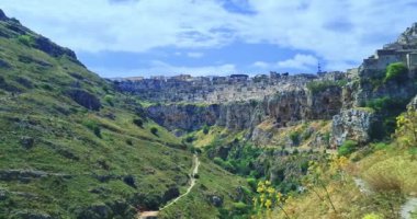 Matera 'da tatil, Gravina di Matera' da Sassi ve Santa Maria di Idris Kilisesi 'nin arka planında doğa, kültür ve doğa kavramının altında yürümek.