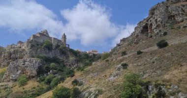 Matera 'da tatil, Gravina di Matera' da Sassi ve Santa Maria di Idris Kilisesi 'nin arka planında doğa, kültür ve doğa kavramının altında yürümek.