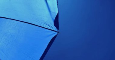 Mavi gökyüzü ve güneş altındaki mavi deniz şemsiyesinin alt görüntüsü, seyahat, tatil ve rahatlama kavramı.,