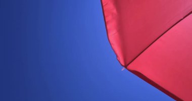 Açık mavi gökyüzü ve güneş altındaki kırmızı deniz şemsiyesinin alt görüntüsü, seyahat, tatil ve rahatlama kavramı.,