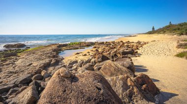 Point Arkwright, Coolum, Sunshine Coast, Queensland 'da kaya havuzu olan volkanik kayalık bir raf. Kumlu sörf plajı boyunca güneye bakıyorum..