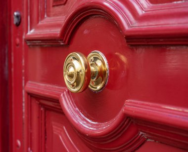 Red front door with shiny brass door knob at the entrance to a house