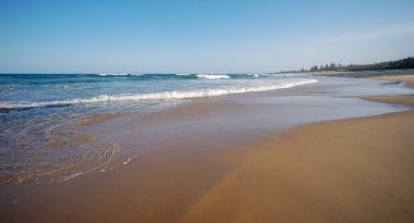 Popüler turizm alanı, Buddina, Günışığı Sahili, Queensland 'da açık mavi gökyüzü ile dalgalı kumlu sahil.