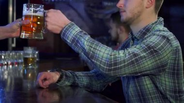 Kahverengi saçlı şık bir beyaz adam barda soğuk bir bira içiyor. Yan profili rahatlamanın özünü yansıtıyor. Barın sıcak atmosferi, kırsal ahşap tezgahı ve...