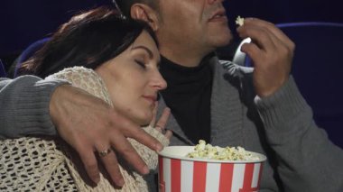 Sıcak bir sinema ortamında, güzel olgun bir kadın kafasını kocasının omzuna koyar, o film ve patlamış mısırın tadını çıkarırken, mutlulukla uyur. Bu samimi an aşkın sıcaklığını yakalar ve...