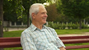 Büyüleyici küçük bir çocuk, güneşli bir parkta elleri ile büyükbabasının gözlerini neşe içinde kapatarak, neşeli bir sürpriz yaratıyor. Yakışıklı beyaz çocuk, parlak bir gülümseme ile, arkasında duruyor