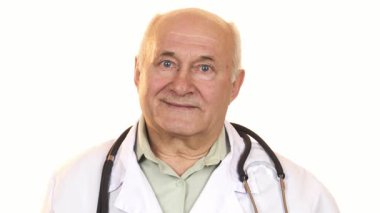 Neşeli, kıdemli bir erkek doktorun sıcak ve davetkar yakın çekimi, el değmemiş beyaz bir arka plana karşı canlı mavi bir hap tutarken gülümsemesini sergiliyor. Bu görüntü profesyonelliği yansıtıyor.