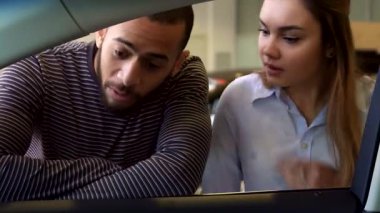 Çekici bir ırklar arası çift galeride şık bir arabanın içini keşfetmek için öne eğiliyor. Yakışıklı Afro-Amerikalı adam, beyaz güzel kız arkadaşı dikkatle dinlerken, gösteriş meraklısı bir şekilde ön paneli işaret ediyor.