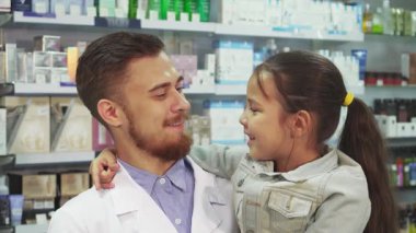 Parlak ve davetkar bir eczanede, genç bir eczacı küçük bir kız beşikte, heyecanlı bir şekilde pencereyi işaret ediyor, keşfetmeye hevesli. Birlikte, renkli raflarla çevrili mükemmel ilacı bulmak için keyifli bir yolculuğa çıkıyorlar.