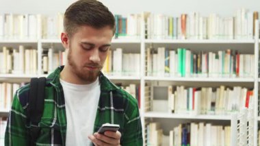 Sıralar dolusu kitaplarla dolu canlı bir kütüphanede, koyu saçlı ve sakallı genç bir adam bir telefon görüşmesi yaparken gülümsüyor. Beyaz bir tişörtün üzerine kareli bir gömlek giymişti. Etrafı ilham verici bir atmosferle çevrili, pozitif ve motive ediciydi.