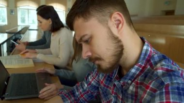 Kendini işine adamış bir kız öğrenci sınıf arkadaşları tarafından çevrelenmiş canlı bir konferans salonunda bilgisayarını kullanıyor. Sahne, derinden konsantre olmuş, düşünceli beyaz bir erkek öğrenciyi, egzersiz kitabı üzerine notlar ve kafa yorarken yakalıyor.