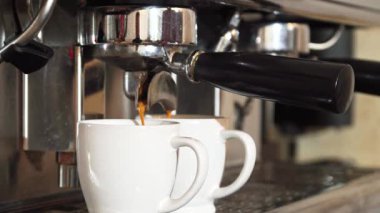 Kahve makinesi, iki zarif beyaz fincana altın sıvıyı dökerek, ustalıkla zengin espresso demlerken enerjiyle mırıldanıyor. Sahne, yetenekli bir baristanın hoş bir kafein deneyimi sunmaya hazır olduğu beklentisini yakalıyor.