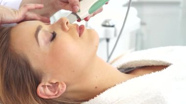 Yetenekli bir kozmetik uzmanı genç beyaz bir kadının pürüzsüz cildini ultrasonik bir şekilde süzüp doğal güzelliğini artırıyor. Salonun sakin atmosferi, ekipmanların hafif uğultusuyla birleşince...