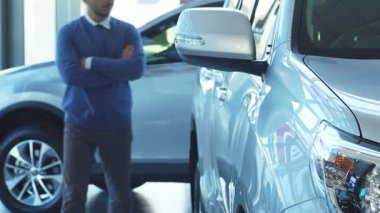 İyi giyimli bir adam pırıl pırıl yeni bir arabaya hayran bir şekilde lüks bir otomobil galerisinde geziniyor. Düşünceli bir gülümseme ile, bir sonraki alışverişini düşünürken, nazikçe cilalanmış araçlara dokunur.