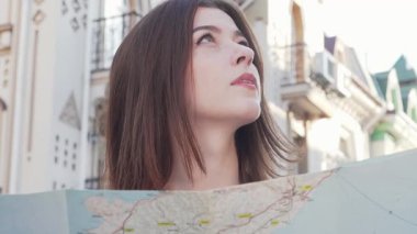 Çekici bir kadın, büyüleyici şehir mimarisi ile çevrili bir haritaya dikkatle bakar. Zevkli bir gezintiye çıkarken, yeni yerler keşfederken yüzündeki ifade merak ve heyecanı yansıtıyor.