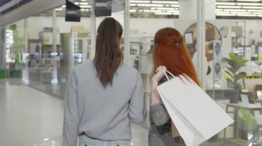 Canlı bir dikiz aynası, her biri şık alışveriş torbaları taşıyan hareketli bir alışveriş merkezinde gezinen iki modaya uygun bayan arkadaşı yakalıyor. Neşeli yoldaşlıkları, son trendleri keşfederken, şehir eğlencelerinin özünü somutlaştırarak ve
