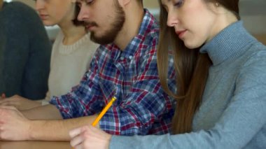 Aralarında sakallı bir adam ve rahat kazaklı bir kadının da bulunduğu bir grup özenli beyaz öğrenci, bir üniversite konferansı sırasında derinden not almakla meşguller. Atmosfer, bilgiyi emerken konsantrasyonla doludur.