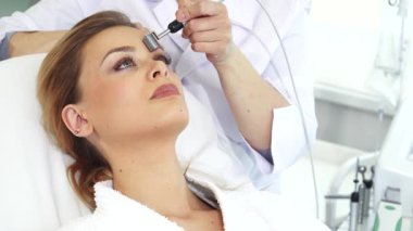 Yetenekli bir kozmetik uzmanı, genç ve sakin bir kadının alnında iyontoforez yuvarlayarak güzelliğini profesyonel bir galvanik yüz tedavisiyle artırıyor. Bu gençleştirici oturum teknolojinin hassas dengesini gösteriyor ve...