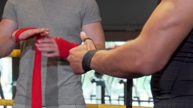 Dinamik bir atış iki erkek boksör yakalar, biri bileğine kırmızı bir bandaj sarar, yoğun bir dövüş için hazırlanırlar. Atmosfer beklenti ve kararlılıkla yükleniyor, bunların ham enerjisini ve odaklanmasını gösteriyor.