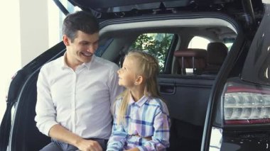 Parlak bir otomobil galerisinde neşeli bir baba ve tapılası kızı şık bir arabanın bagajında kameraya ışıldıyor. Küçük kız bir araba anahtarı tutuyor, heyecan ve macerayı simgeliyor, baba ise gurur yayıyor.
