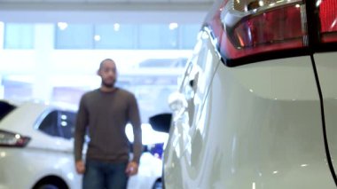 Şık, esmer bir adam, modern bir otomotiv deneyimi sergileyerek, galeride parlak bir kesişme noktasına adım atar. Görüntü, Afrika kökenli Amerikalı genç bir adamın hareketli stop ışıklarıyla arabanın kapısını açtığı uzun bir görüntüyü yakalıyor.