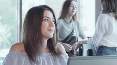 Uzun, dalgalı saçlı çekici bir kadın canlı bir kahve dükkanında dizüstü bilgisayarına odaklanmış, yaratıcılık ve hırs saçıyor. Yumuşak güneş ışığı ve taze kahve kokusuyla dolu ılık ortam düşünceli yüz ifadesini geliştirir.