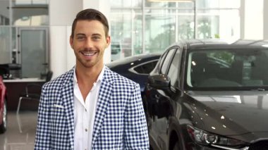 Gösterişli bir araba galerisinde kredi kartını tutan şık sakallı ve koyu renk saçlı keyifli bir adam. Kareli ceket ve beyaz gömlek giymişti. Heyecan saçıyordu. Yeni araba alımını kutluyordu.