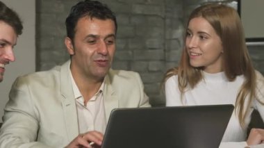 Canlı bir sahne, animasyon sohbetlerinde yer alan ve bir dizüstü bilgisayarla fikirleri paylaşan çeşitli iş dünyasından profesyonelleri yakalıyor. İfadeleri güven ve pozitiflik yayar, modern bir ofiste takım çalışması ve yenilik ruhunu somutlaştırır.