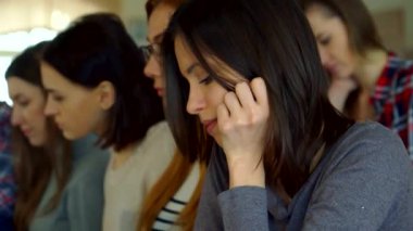 Neşeli genç bir kız öğrenci, çenesi elinde dinlenen hareketli bir konferans salonunda güven içinde poz veriyor. Bu çekici esmer, sıcak bir gülümseme ile, nişanlı sınıf arkadaşları arasında akademik coşkunun özünü yakalıyor.