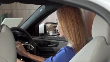 Dalgalı saçlı ışıl ışıl bir kadın yeni lüks arabasında kameraya parlak bir şekilde gülümsüyor. Gösterişli bir galerideki bu büyüleyici sahne, zarafet ve modernliği somutlaştıran rüya bir araç satın almanın heyecanını yakalıyor.