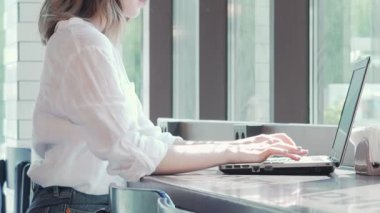 Güzel bir bayan girişimcinin büyüleyici bir sahnesi. Parlak, davetkar bir kahve dükkanındaki dizüstü bilgisayarına derinden odaklanmış. Sıcak güneş ışığı pencereden süzülerek serbest projelerini yönetirken düşünceli yüz ifadesini aydınlatıyor.