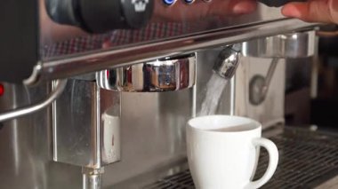 Yetenekli bir barista, kahve makinesinin ışıldayan beyaz bir fincana zarif bir şekilde kaynar su eklemesiyle hazır duruyor. Bu yakın plan, kahve yapma sanatının sanatını yakalıyor ve canlanan zengin bir biranın beklentilerini gözler önüne seriyor.