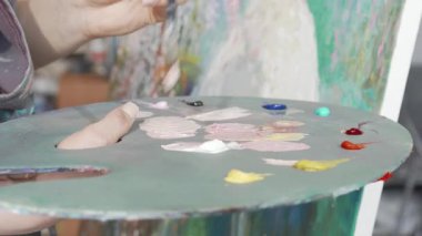 Bir kadın ressam paletinin yakın plan görüntüsü bir sonraki başyapıtı için boyaları ustalıkla karıştırırken çarpıcı bir renk dizisi ortaya çıkarıyor. Bu sanatsal sahne yaratıcılığın ve tutkunun özünü yakalıyor ve onun karmaşık detaylarını gözler önüne seriyor.