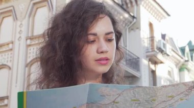 Neşeli genç bir kadın, büyüleyici bir şehir manzarasını keşfederken elinde renkli bir haritayla yukarıya bakıyor. Bu canlı sahne macera ve merakın özünü yakalıyor, izleyicileri keşif yolculuğuna davet ediyor.