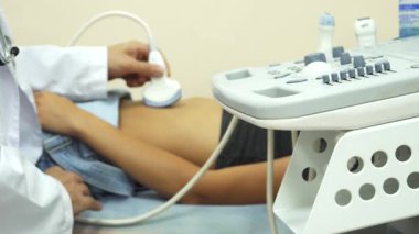 Huzurlu bir doktorun muayenehanesinde, şefkatli bir doktor genç bir kadının elini dikkatlice muayene eder ve onun rahatını ve sağlığını sağlar. Olay yeri tıbbi ekipmanlarla dolu. Bu önemli konsültasyon için profesyonel ama davetkar bir ortam yaratıyor.