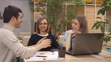 Karizmatik bir genç adam, modern ofis ortamındaki iki ilgili bayan meslektaşına kavramları anlatırken hareketli bir şekilde hareket eder. Sahne canlı bir yeşillik ve rahat bir atmosferle dolu. Laptop ve kahve üzerinde işbirliği yapıyorlar.