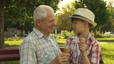 Neşeli, kıdemli, beyaz bir adam ve sevimli torunu, canlı bir park bankında dondurma yerken keyifli bir anı paylaşıyorlar. Yakışıklı küçük çocuk, şık bir şapka takıyor, sevinçle parıldıyor ve dedesi ve o, yürek ısıtan bir iş yapıyor.