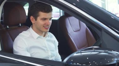 Koyu renk saçlı neşeli genç bir adam yeni bir arabanın direksiyonunu sıkıca tutarak sürücü koltuğuna rahatça oturur. Parlak gülüşü, lüks iç mekanları keşfederken heyecan saçıyor. Seyircileri otomotiv dünyasına davet ediyor.
