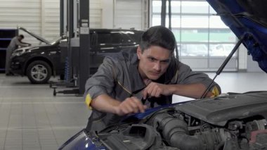 Kendini işine adamış erkek bir tamirci titizlikle bir arabanın açık kaputunun üzerine eğilip parlak, parlak bir garajda motoru inceliyor. Bu sahne otomotiv uzmanlığının özünü ve hızlı bir şekilde kaliteli servise olan bağlılığını yakalar.