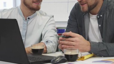 Kesilmiş bir fotoğraf, biri sakallı, diğeri genç iki erkek meslektaşını, şık bir ofis masasında kahve içerken canlandırıcı bir şekilde iş tartışırken yakalıyor. Odaklanmış ifadeleri ve jestleri dinamik bir ortaklık, işbirliğini vurguluyor
